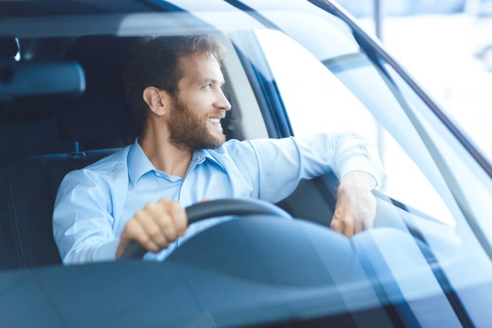 Zadowolony mężczyzna w nowym zarejestrowanym samochodzie
